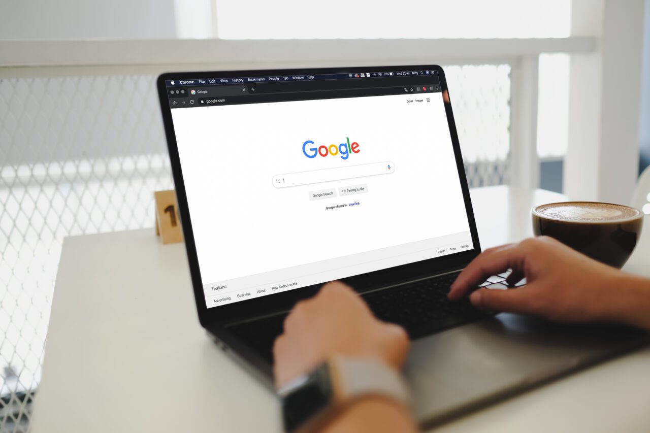 A woman is typing on Google search engine from a laptop.